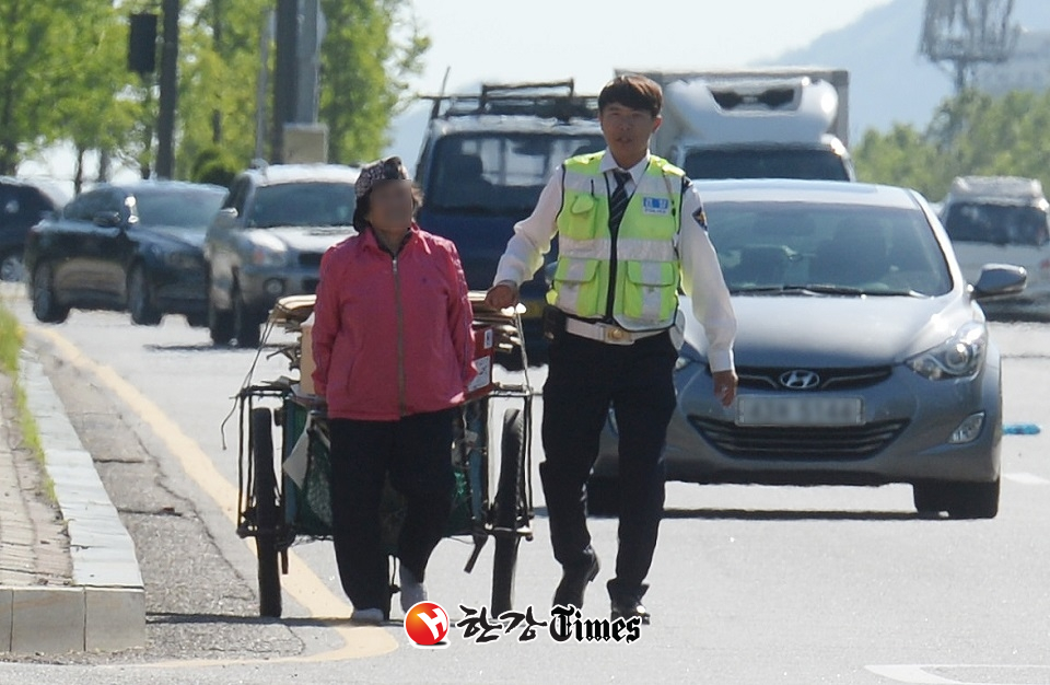 서울 구룡마을 인근 양재대로에서 한 폐지 수집 할머니가 리어카를 끌고 위험천만하게 도로를 걷자 순찰 중이던 경찰관이 보호하며 함께 걷고 있다. (사진=뉴시스)