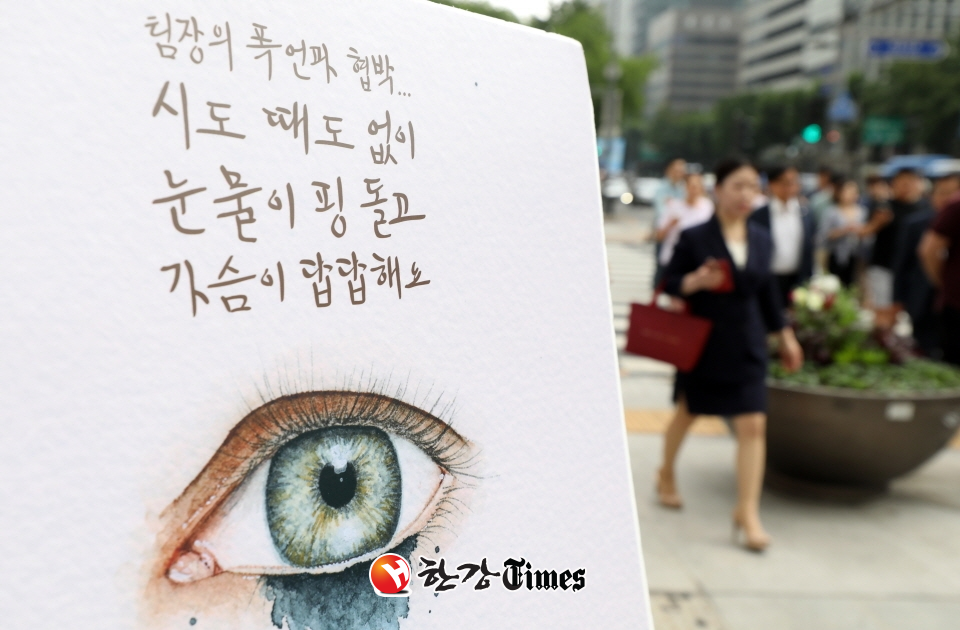 16일 오전 서울 종로구 광화문 광장 네거리에서 열린 갑질금지법 시행 맞이 캠페인에 설치된 판넬 앞을 시민들이 지나고 있다. 사진=뉴시스