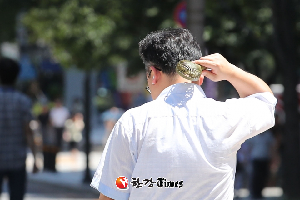 서울지역에 폭염 경보가 발령된 8일 오후 서울 종로구 광화문광장에서 한 시민이 선풍기를 목에 쐬고 있다.