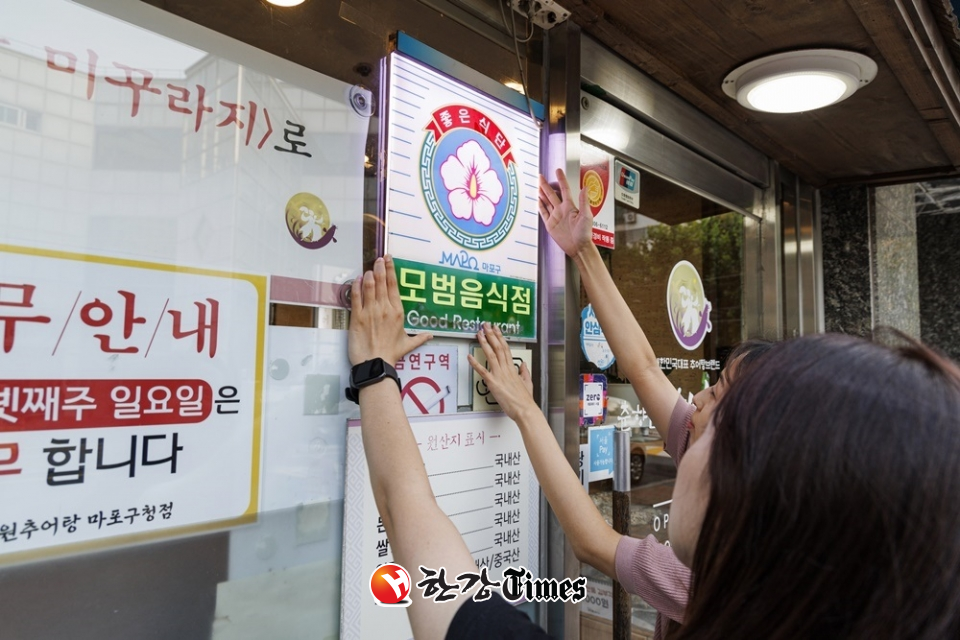 마포구 직원이 모범음식점으로 지정된 관내 음식점에 표지판을 설치하고 있다